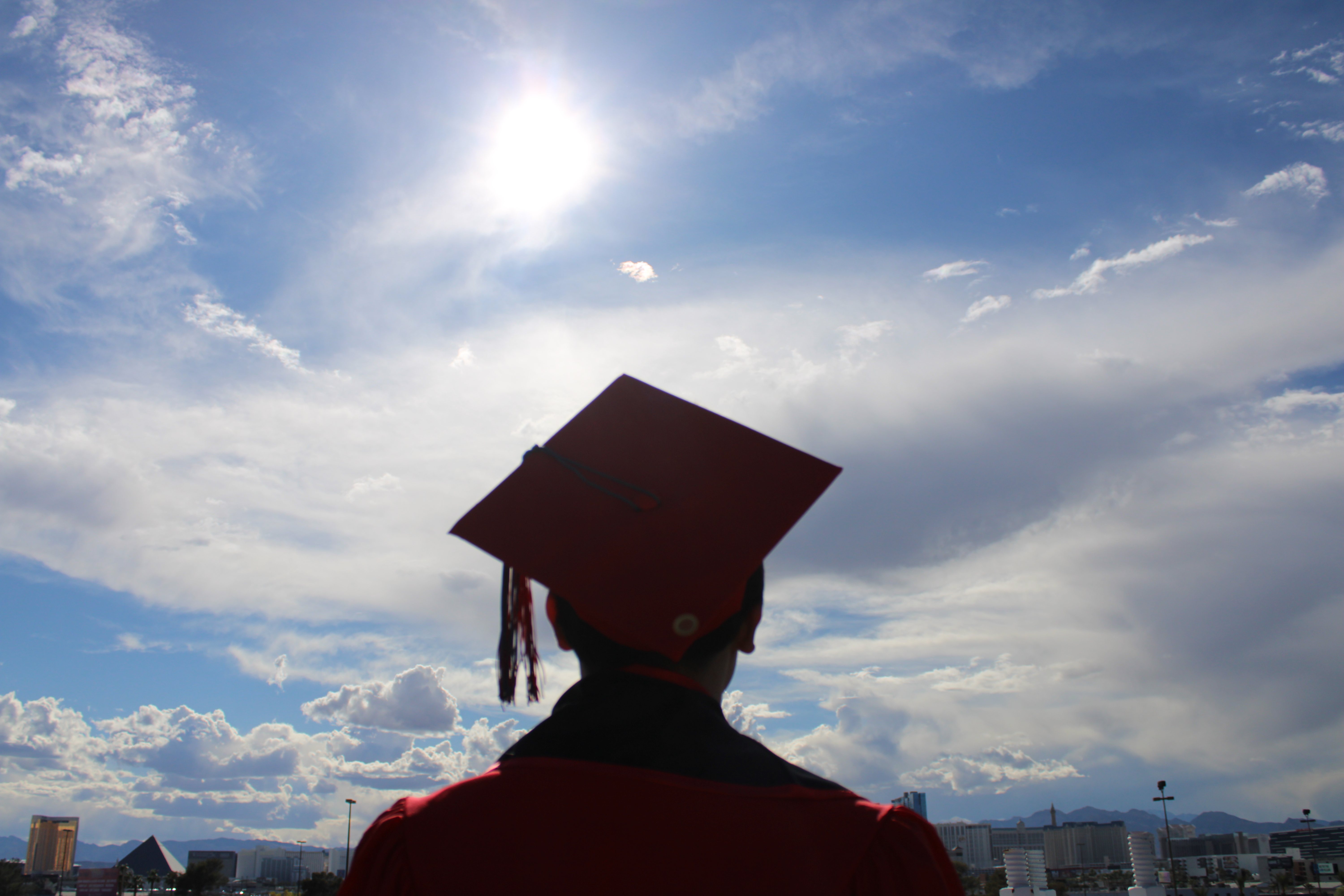Commencement portrait of Mark Jayson Farol in graduation regalia against the Las Vegas skyline.